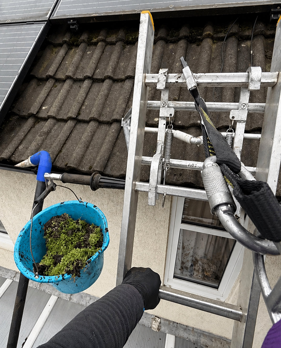 Roof moss removal in progress with safety equipment on a Leicester home