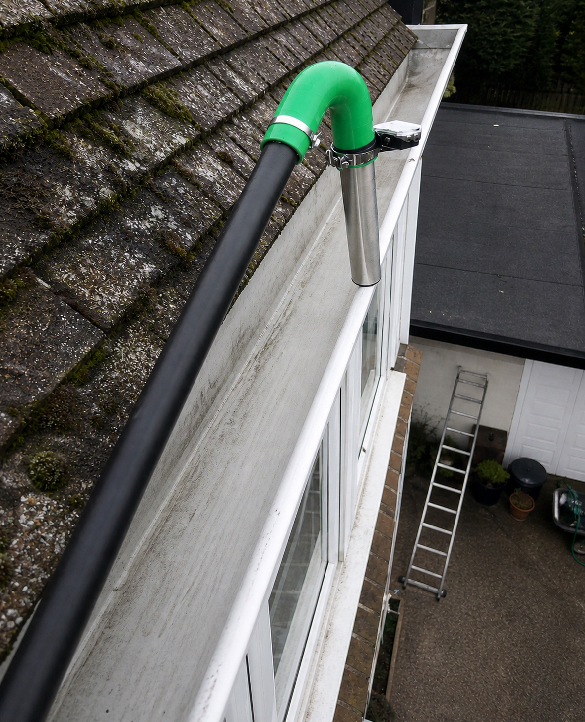 High-reach gutter vacuum cleaning system reaching a first-floor gutter safely from the ground